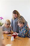 Volunteer watching senior women playing cards at table in community center