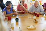 Senior friends playing games at table in community center