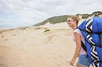 Smiling female paraglider with parachute backpack on beach