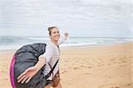 Portrait smiling, carefree young female paraglider with parachute backpack on ocean beach