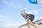 Male paraglider running with parachute on beach