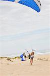 Female paraglider with parachute on ocean beach