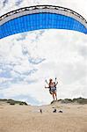 Female paraglider with parachute taking off on beach