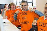 Portrait confident hackers in t-shirts coding for charity at hackathon