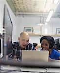 Businessman and businesswoman using laptop in office