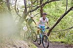 Men mountain biking on trail in woods