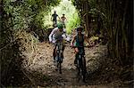 Friends mountain biking on trail in woods