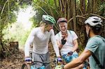 Male friends mountain biking, using smart phone in woods