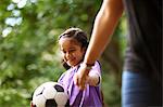 Smiling girl with soccer ball holding hands with mother