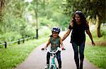 Happy mother teaching daughter how to ride bike