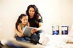 Mother and daughter with digital tablet preparing painting project