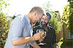 Happy male gay couple drinking wine in sunny garden