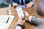 Close up of a businessman reviewing data on smart phone in corporate office. Focus on mobile device.