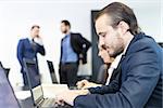 Workplace in modern corporate office with business people brainstorming. Businessman working on laptop during the meeting.