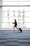 Businesswoman running through a conference centre lobby.