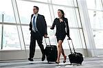 Male and female business people running past a window in the lobby of a conference centre