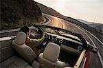 A view from behind of a Caucasian male driving a convertible sports car in eastern Washington State, USA.