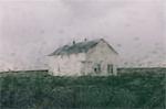 Abandoned farmhouse in a rainstorm, seen through a wet window. Blurred image.