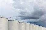 Rows of grain silos, stormy skies in distance, Saskatchewan, Canada.