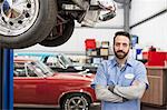 A portrait of a Caucasian mechanic in his classic car repair shop.