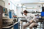 A male Caucasian technician sitting at a workbench at a technical research and development site.