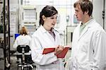 A team of two male and female technicians working over a problem in a technical research and development site.