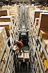 Looking down on an employee picking a box out of a rack, while standing on a motorized stock picker in a distribution warehouse.