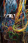 Asian female technician working on a tangled mess of CAT 5 cables in a server room.