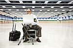 A Hispanic businessman looking at a laptop computer sitting at a small desk in the middle of a convention arena.