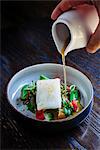 Pouring broth on halibut with lemon, peas, melon, beets and herbs