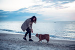 Young woman playing with pet dog on beach