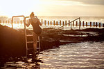 Woman climbing up coastal pool ladder, Las Palmas, Gran Canaria, Canary Islands, Spain