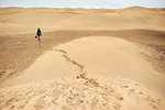 Mature female tourist walking barefoot on sand dune, rear view, Las Palmas, Gran Canaria, Canary Islands, Spain