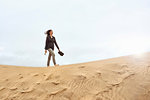 Female tourist walking barefoot on sand dune, Las Palmas, Gran Canaria, Canary Islands, Spain