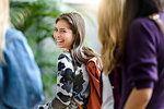 Female university students walking and talking in university lobby, cropped