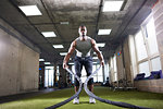 Man using battle ropes in gym