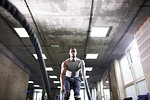 Man using battle ropes in gym