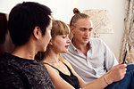 Young woman and male friends looking at smartphone on bed