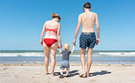 Parents walking with toddler on beach