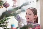 Girl decorating, hanging ornament on Christmas tree