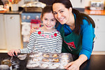 Portrait smiling mother and daughter baking in kitchen
