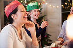 Happy family in paper crowns laughing at Christmas dinner