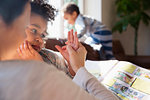 Affectionate mother and daughter holding hands, reading book