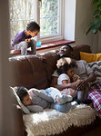 Father and children relaxing, cuddling on living room sofa