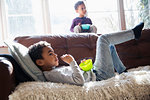 Brothers relaxing, watching TV and enjoying snack on living room sofa