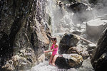 Girl playing in waterfall, Tofino, Canada
