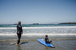 Father and daughter surfing on beach, Tofino, Canada