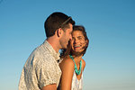 Romantic young couple laughing against blue sky