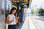 Businesswoman using cellphone by ticket machine