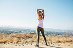Woman doing stretching exercise on hilltop, Los Angeles, US